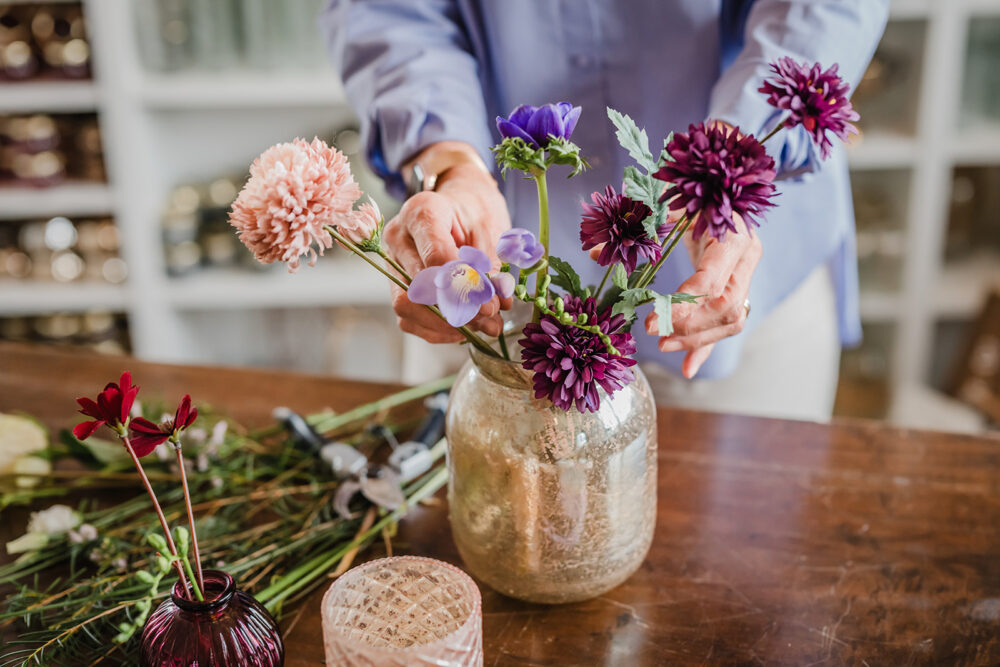 Hände drapieren einen Blumenstrauß in einer Vase