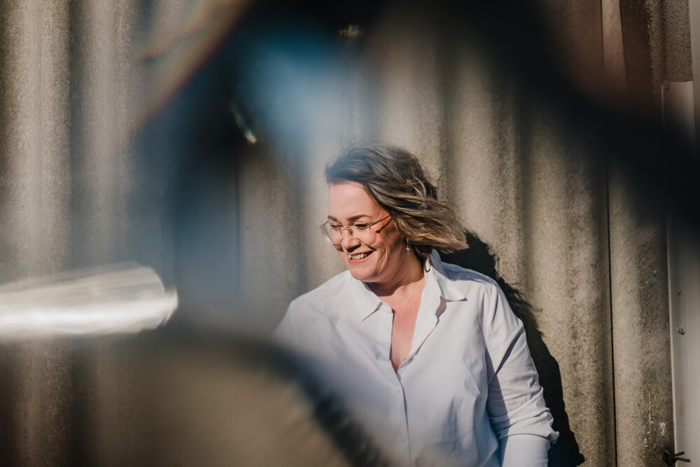 Lächelnde Fotografin vor einer Wand zwischen Schatten und Spiegelungen