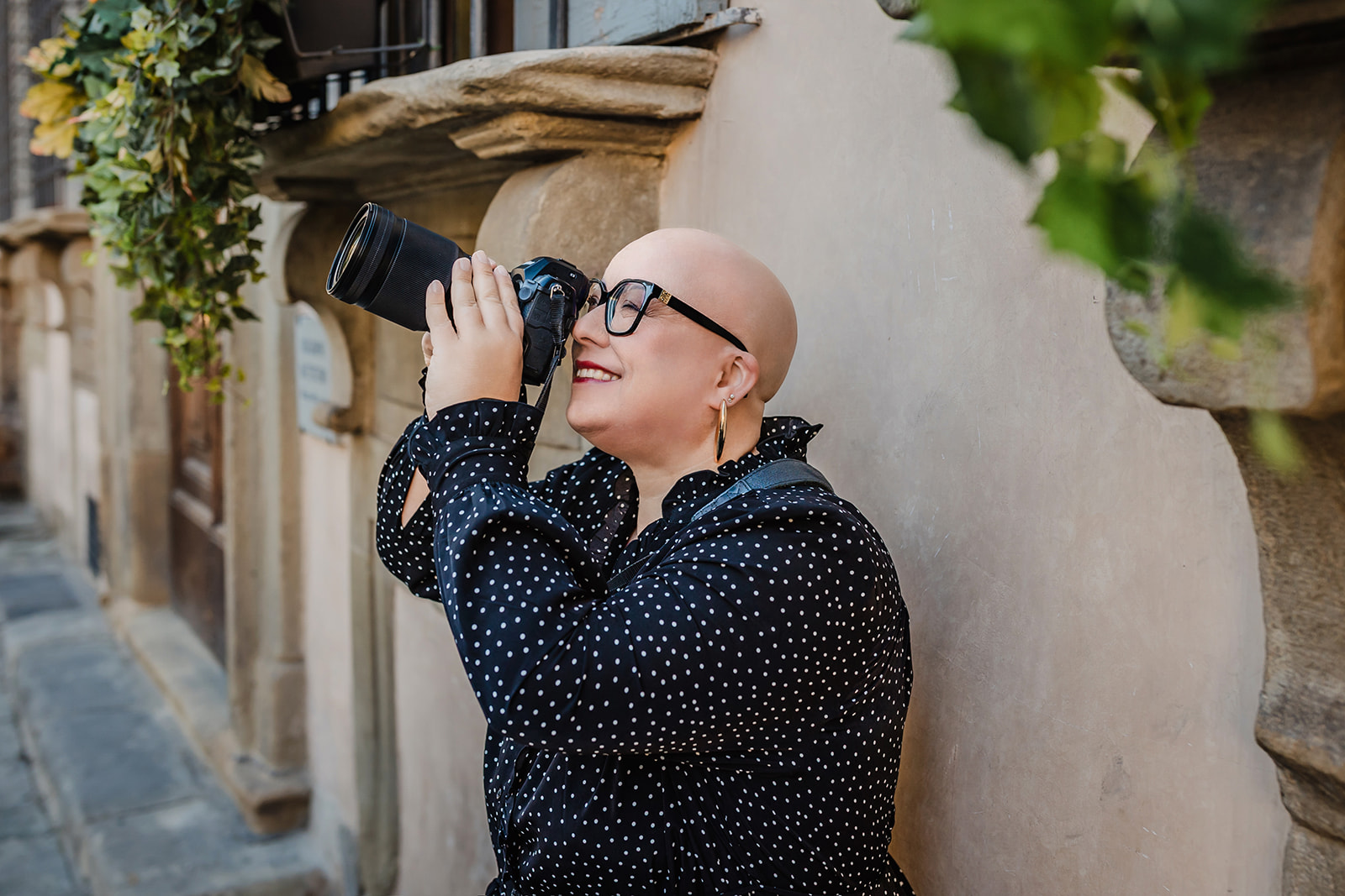 Fotografin lehnt an einer Wand in Florenz und blickt gen Himmel durch ihre Kameralinse Fotografin lehnt an einer Wand in Florenz und blickt gen Himmel durch ihre Kameralinse, Schwarz-weiß-Bild
