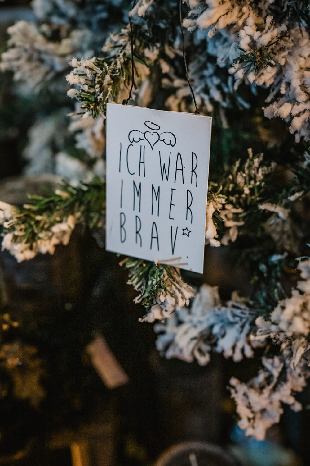 Weihnachtlicher Anhänger an Tannenzweigen mit der Aufschrift